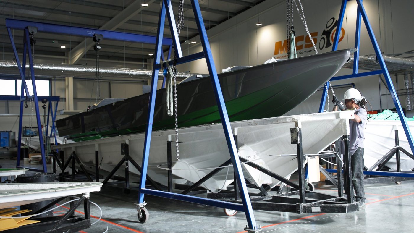 Composite boat hull being lifted from its mould on gantry cranes